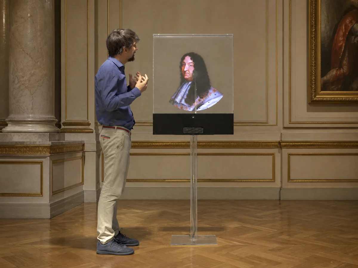 A visitor interacting with a digital representation of Louis XIV in a royal museum setting.