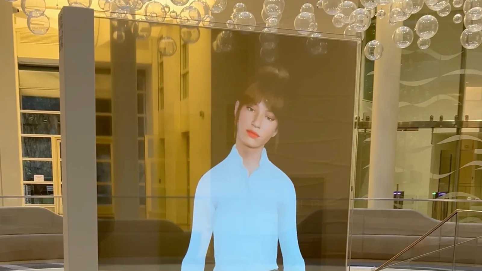A digital host presented on a transparent HoloAI display inside an Axcess lobby in Paris