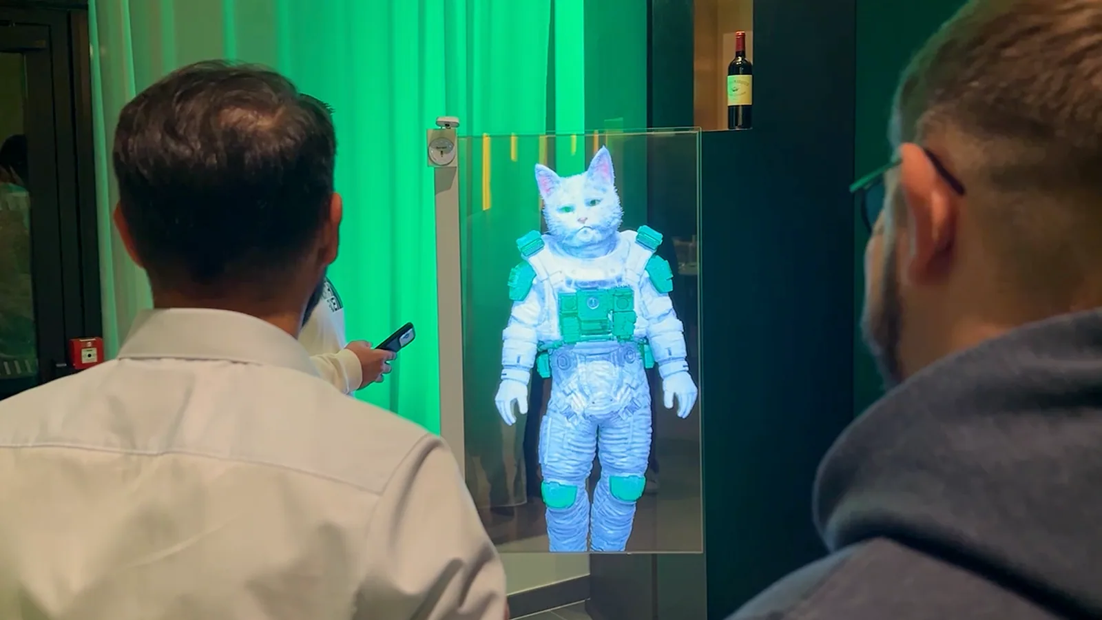 Visitors speaking with the Feu Vert cat mascot on a transparent HoloAI display