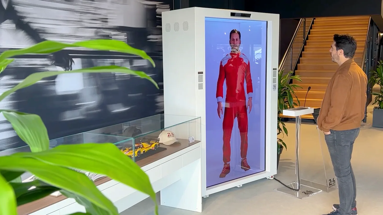 A visitor interacting with a fictional racing driver on a HoloAI display at the 24 Hours of Le Mans
