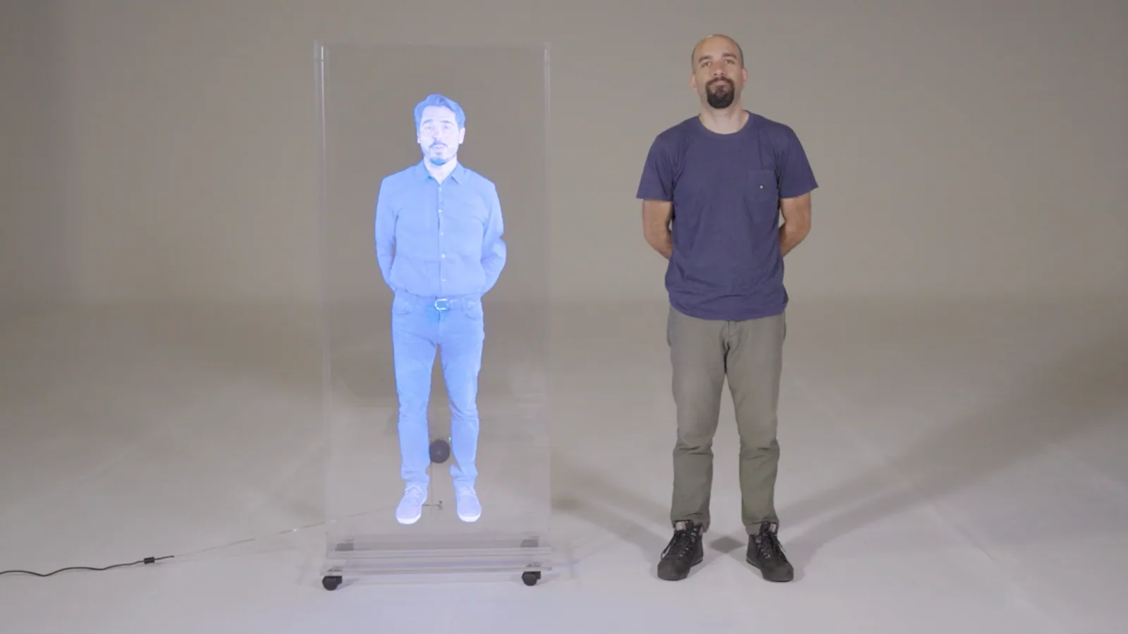 A man standing beside his life-size holographic representation